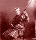 Studio portrait of a young man in a striped chapan with a long-necked lute