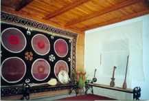 Interior hung with a suzani, with tanbur, dutar and frame drum on a bench